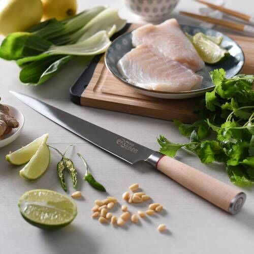 Image of ProCook Nihon X50 carving knife resting on a kitchen worktop beside filleted fish