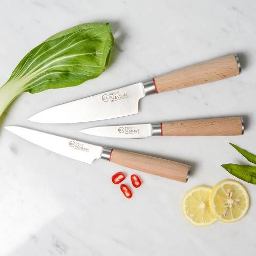 Image of ProCook Nihon X50 Knife Set laying flat beside sliced chillis, bak choy and lemon